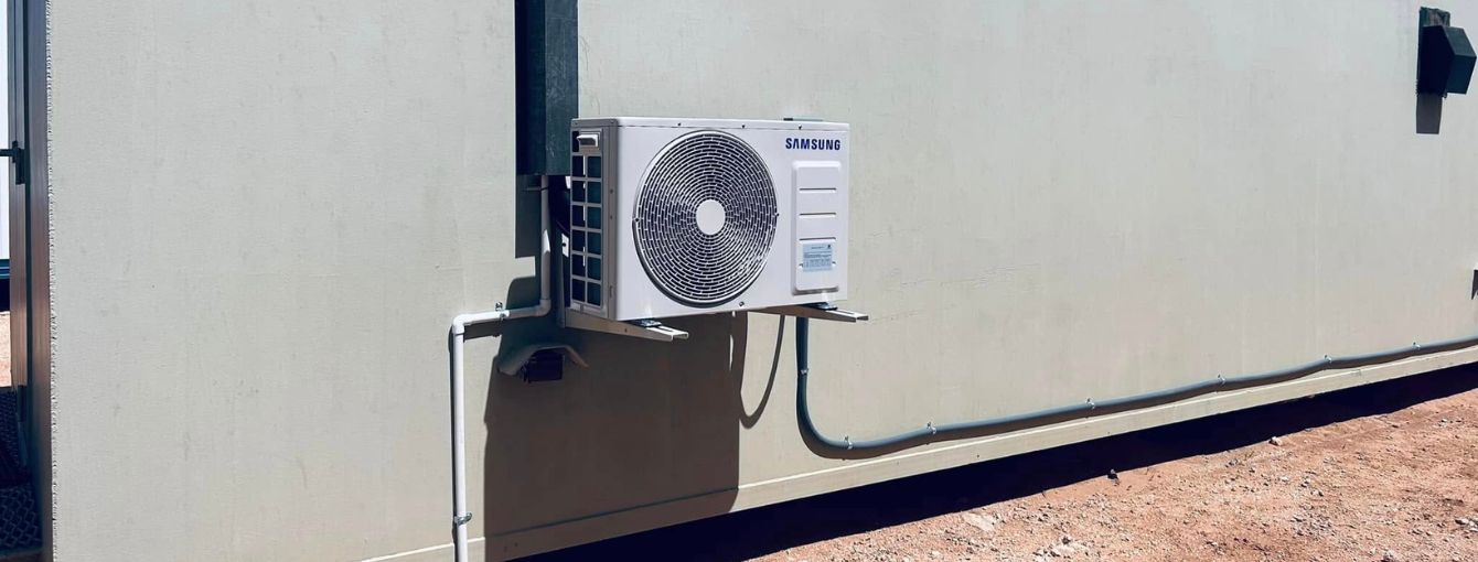 A heat pump is installed on the side of a building. 