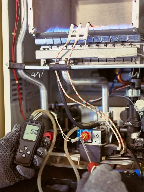 An HVAC Technicians working on a heater.