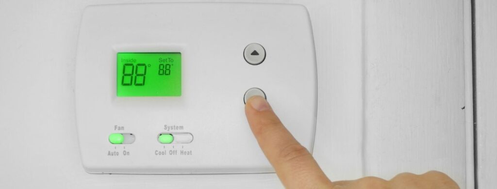 A person programming a thermostat.
